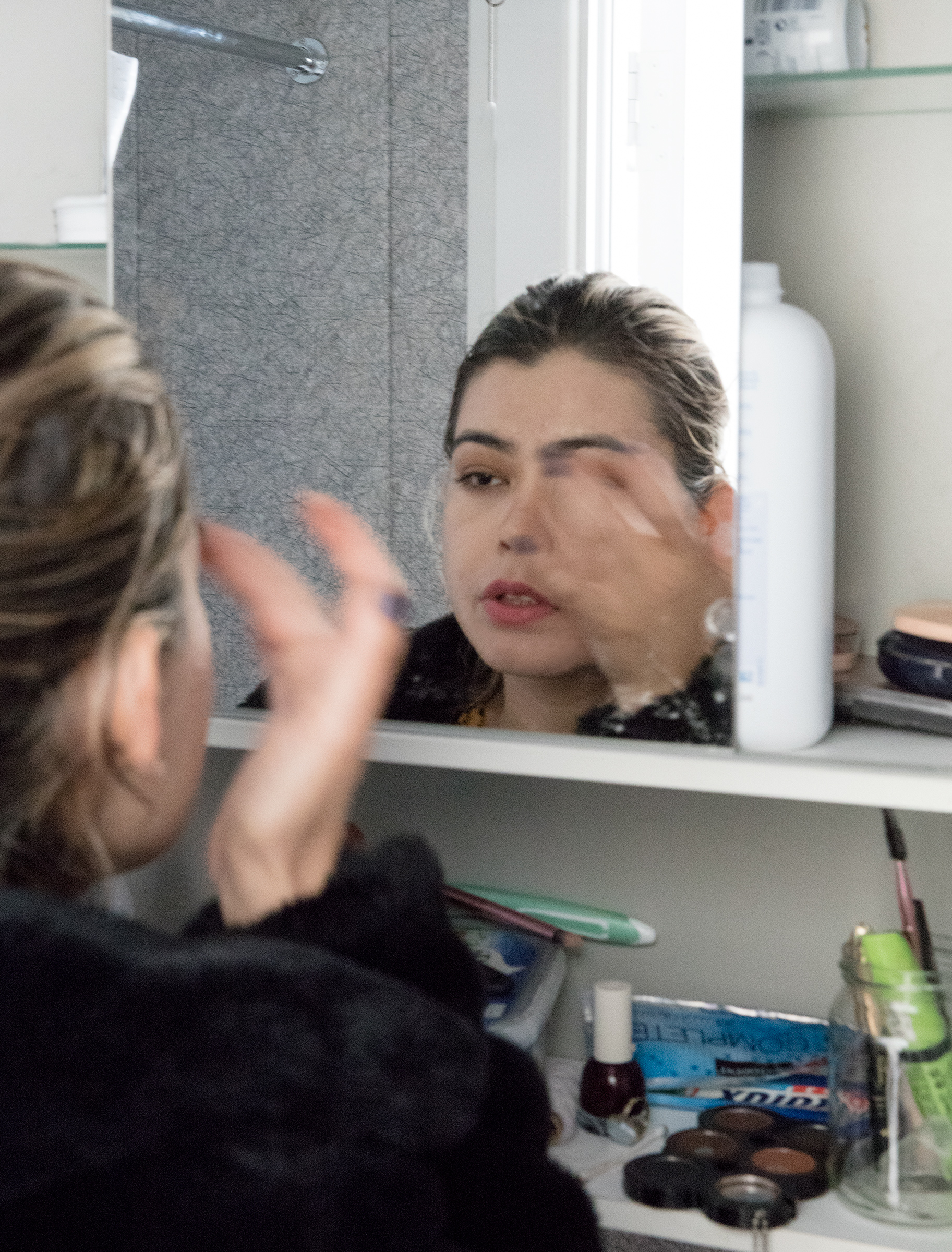 Basira applying makeup in her bathroom