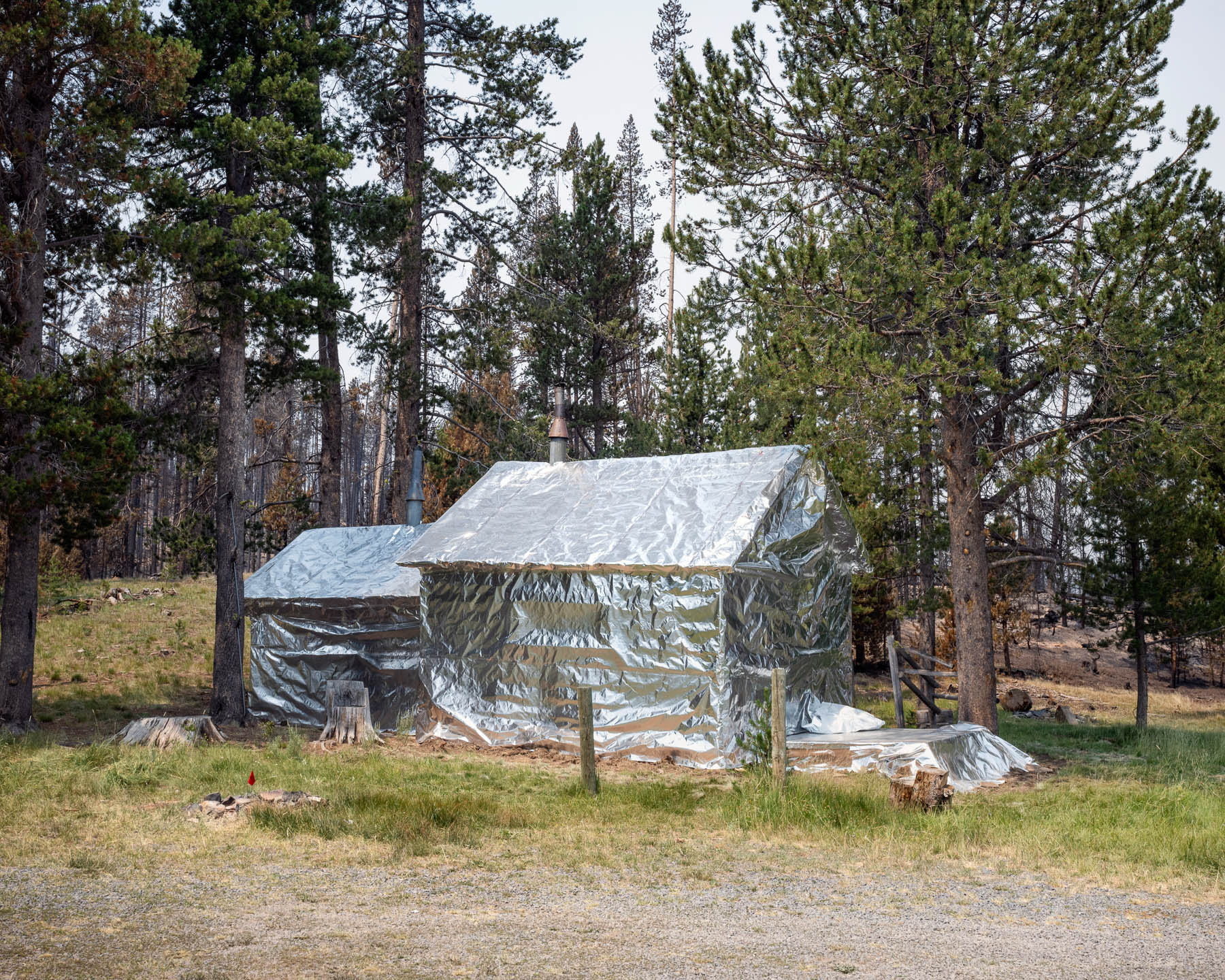 In advance of the Bootleg Fire's approach on July 23, a structure was wrapped in fire-retardant protective sheeting in a bid to save it from the flames. Forestry officials found it had been [caused by lightning](https://www.reuters.com/world/us/lightning-found-have-ignited-oregons-mammoth-bootleg-fire-2021-07-22/) and went undetected for days before July 6, when it was reported. The fire, which for a time was America’s largest of the year, burned more than [413,000 acres](https://inciweb.nwcg.gov/incident/7609/) and led to the evacuation of [some 2,000 homes](https://apnews.com/article/science-fires-environment-and-nature-wildfires-3f102582aa78c2400a95374a2fb07529). By Aug. 15, it was 100% contained.